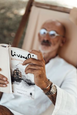 Elderly ethnic man reading interesting book in nature